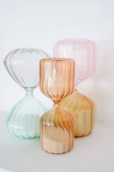 three glass vases sitting side by side on a white surface, one with an upside down design