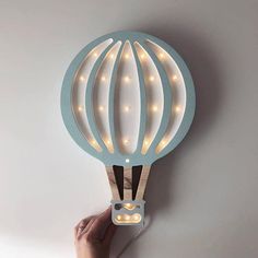 a light up hot air balloon with lights on it's sides is being held by a hand