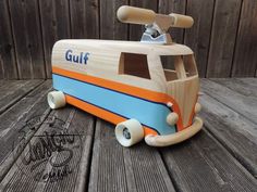 an orange and blue toy bus sitting on top of a wooden floor next to a fence