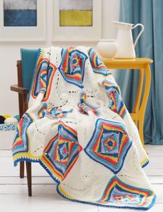 a crocheted blanket is sitting on a chair in front of a table and chairs