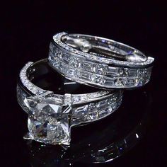 two diamond rings sitting on top of each other in front of a black background,