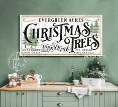 there is a christmas tree sign on the wall next to a kitchen counter with dishes and utensils