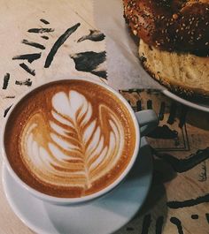 there is a cup of coffee and a bagel on the table next to it