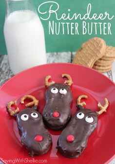 three chocolate reindeer cookies on a red plate next to a glass of milk and some pretzels