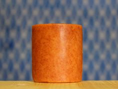 a wooden cup sitting on top of a table next to a blue and white wall