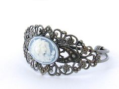 "Two Sisters Cameo Bracelet/Victorian Cameo Bracelet/Cameo/Victorian Cameo Jewelry/Sisters Cameo/Silver Cameo Cuff Bracelet/Wedding Jewelry Victorian Cameo Cuff Bracelet featuring two sisters 25 x 18 mm cameo on a black background set in an antiqued pewter filigree cuff bracelet. Also available in blue. Beautifully detailed antiqued pewter finished brass cuff adjusts to comfortably fit a wrist between 5.75 and 7.75 inches. This is a popular gift for sisters and best friends. Brides - Please conv Victorian Cuff Bracelet For Wedding, Antique Adjustable Cuff Bracelet For Wedding, Vintage Antique Silver Cuff Bracelet, Antique Silver Cuff Bracelet For Wedding, Silver Cameo Bracelet For Gifts, Vintage Antique Silver Cuff Bracelet For Wedding, Antique Cameo Bracelet For Wedding, Vintage Silver Cameo Bracelet, Ornate Antique Silver Cuff Bracelet For Weddings