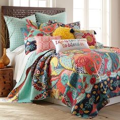 a bed with colorful comforters and pillows