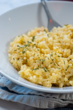 a white plate topped with rice covered in seasoning next to a fork and napkin