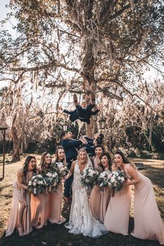 the bride and groom are posing with their bridal party in front of a tree