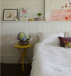 a bed with white sheets and pillows next to a painting on the wall above it