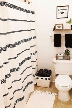 a white toilet sitting in a bathroom next to a shower curtain with black and white designs on it