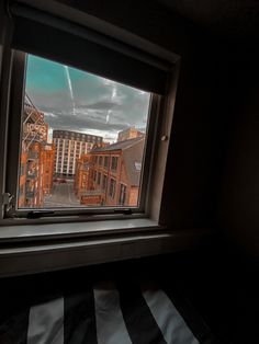 a window with buildings seen through it in an apartment building's dark room, looking out onto the street