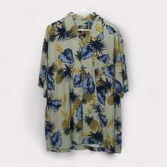 Bring island vibes to your wardrobe with this La Cabana Men’s Hawaiian Lounge Shirt in a relaxed, tropical floral print. Featuring a beautiful beige background with bold blue and yellow leaves and pineapple accents, this shirt is perfect for summer outings, vacation wear, or casual lounging. Made from lightweight rayon, it offers a soft, comfortable fit that’s easy to wear and care for. • Brand: La Cabana • Size: XL • Color/Pattern: Beige with blue and yellow tropical floral and pineapple print Affordable Green Casual Hawaiian Shirt, Lounge Shirt, Summer Gathering, Vintage Trucker Hats, Tropical Floral Print, Vacation Wear, Island Vibes, Pineapple Print, Yellow Leaves