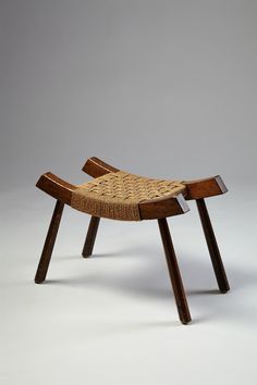 a wooden bench with woven seat padding on the back and legs, against a gray background