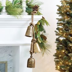 a christmas tree with bells hanging from it's sides next to a fire place