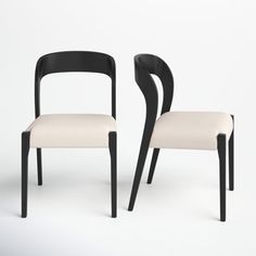 two black and white chairs sitting next to each other on a white surface with no one in it