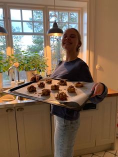 a woman holding a tray full of cookies