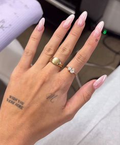 a woman's hand with pink and white nail polish on it, holding up her ring