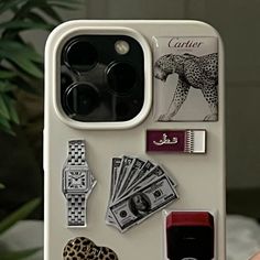 a person holding up a phone case with various items attached to the back of it