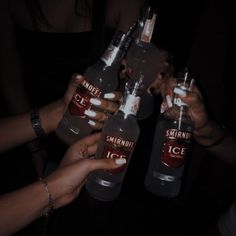 three people holding up two bottles of ice