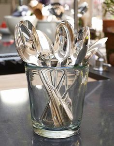 a glass cup with spoons and forks in it