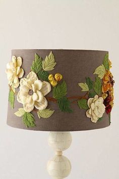 a lamp that has flowers on it and green leaves around the lampshade,