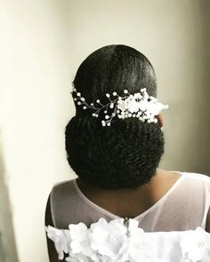 the back of a woman's head with flowers in her hair, wearing a white dress