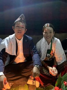 two people sitting next to each other in front of a cake with lit candles on it