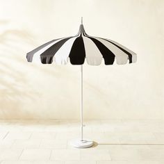 an umbrella is standing on the floor in front of a white wall and tiled floor