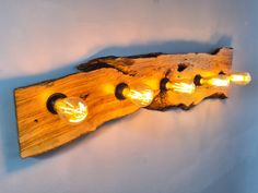 three light bulbs are attached to a piece of wood that has been carved into it