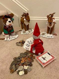 three stuffed animals sitting on the floor next to piles of coins and playing cards with them