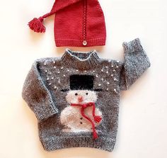 a knitted snowman sweater and hat on top of a white surface with a red pom - pom