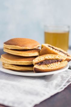 a stack of pancakes sitting on top of a white plate next to a glass of beer