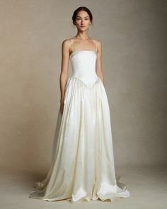 a woman in a white wedding dress standing on a gray background with her hands behind her back