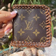 a woman holding up a brown wallet with gold lettering on the front and bottom side