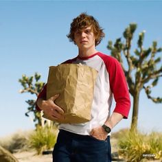 a young man holding a brown paper bag