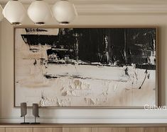 an abstract painting hangs on the wall above a cabinet in a room with white and black accents