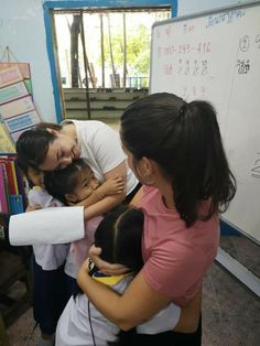 a group of people hugging each other in front of a whiteboard with writing on it