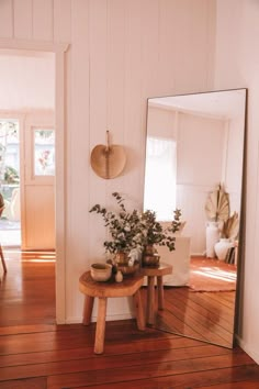 there is a mirror on the wall next to a table with flowers in vases