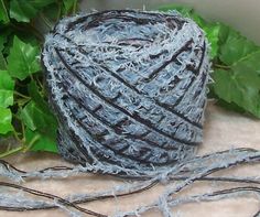 a ball of yarn sitting on top of a table next to some green plants and leaves