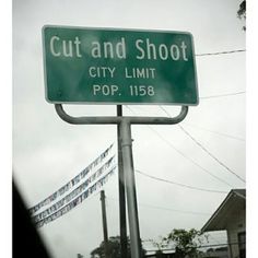 a green street sign that reads cut and shoot city limit pop 1388 on it