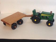 a toy tractor pulling a wooden cart with wheels on white paper and black rubber rims