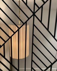 a lamp that is sitting on a table next to a wall with black bars in it