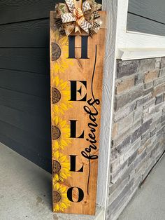 a wooden sign with the word hello written on it and sunflowers painted on it