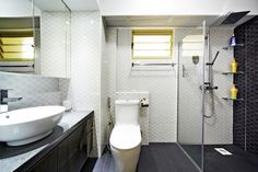 a white toilet sitting in a bathroom next to a sink and bathtub on top of a wooden floor