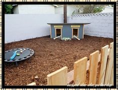 a dog house with a trampoline on the ground and a toy train set in the yard