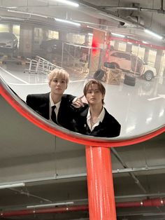 two young men in suits are looking at themselves in a mirror that is reflecting them