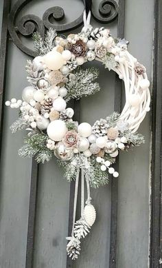 a wreath hanging on the side of a door with pine cones and other decorations around it