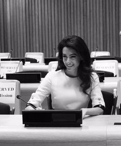 a woman sitting at a table with a laptop computer in front of her, smiling