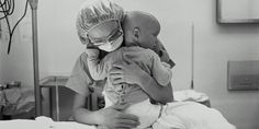 a woman holding a baby in her arms while sitting on top of a hospital bed